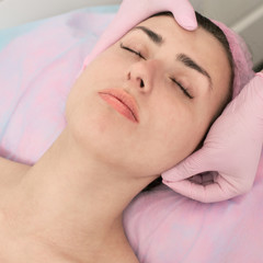 Fototapeta na wymiar Young woman lying with closed eyes and having head massage in spa
