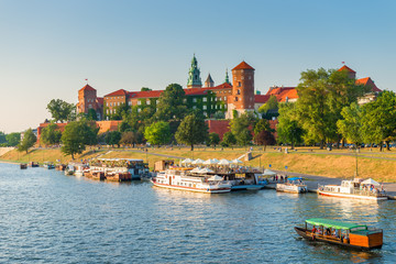 Obraz premium Krakow, Poland - August 11, 2017: panoramic view of the famous Wawel Castle, located on a hill, boats in the Wisla River