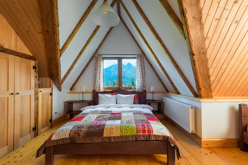 bedroom interior in a wooden house with a beautiful view from the window to the mountains
