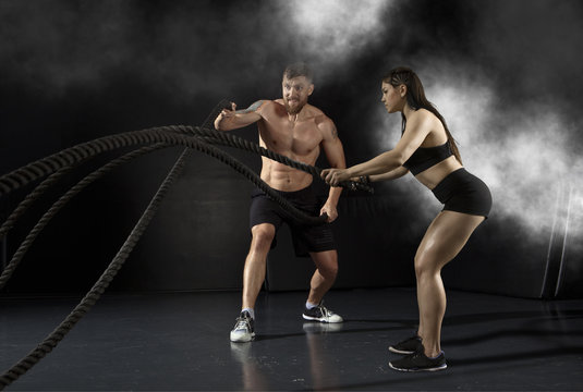 Woman and men working out with battle ropes