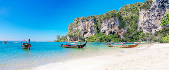 Obraz premium Amazing landscape with traditional longtail boats, rocks, cliffs, beautiful sea tropical and white Tonsai beach. Popular famous travel vacation destination Krabi Province, Thailand.
