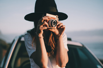 young woman taking picture with retro camera on roadtrip