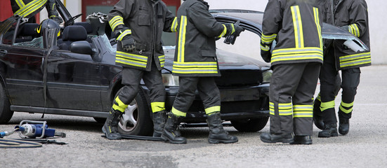 firefighters engaged in removing the wreckage of a car