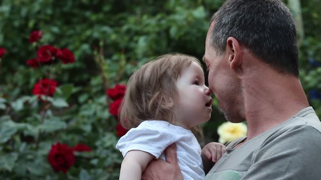 Smiling father and one year old girl. Happy father with daughter on background of flowers. Adult male with gray hair