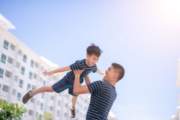 Happy father and son playing together having fun outside the Condominium or apartment building.