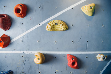 Close-up of hooks for rock climber on wall. Multicolored background.