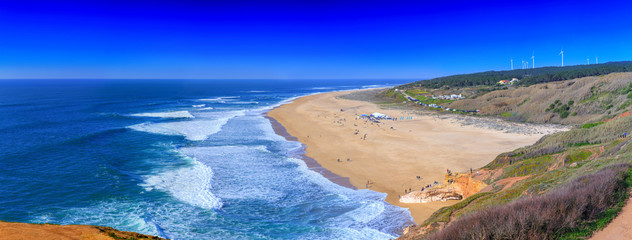 Fototapeta na wymiar Awesome aerial sunny seascape coastline of Atlantic ocean. View North Beach (Praia do Norte). Most famous place of giant breaking waves for surfers from around the world. Nazare, Portugal.