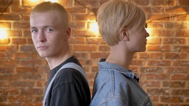 Young extraordinary couple of hipsters is dancing with necks, boy turns to camera, move conception, brick conception