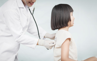 Selective focus Professional pediatrician examining to a girl. Doctor using a stethoscope to listen to girl's chest checking heartbeat or lung.