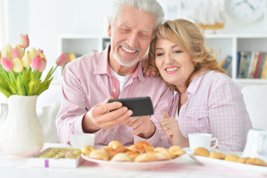 senior couple with smartphone drinking tea