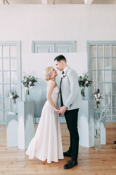 Beautiful wedding in European style, in light blue colors. Couple in the Studio on the background of an unusual arch, inspiration. Laughing bride and handsome groom