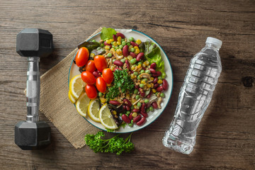 Healthy food , dumbells and bottle of water on the  wooden table ,Fitness and health concept.