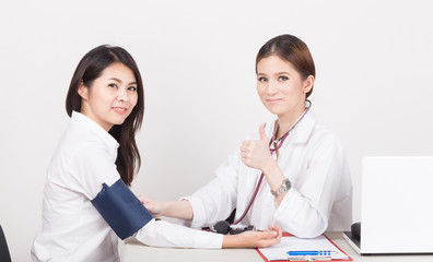 Doctor using sphygmomanometer with stethoscope checking blood pressure  to a patient in the hospital.