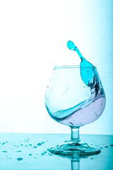Splash of blue water in a glass. White Blue Background.