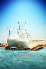 A jug of milk and glass of milk on a wooden table