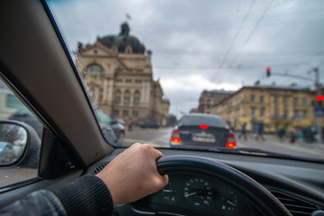 first-person view. man driving car by city streets. urban traffic