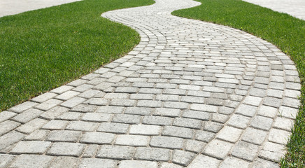 Curved path in the shape of a wave on the grass in the Park. Paved with tiles of different shapes. - Powered by Adobe