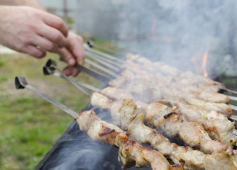 Man cooking, only hands, he is cutting meat or steak for a dish. Delicious grilled meat on grill. Barbecue weekend.