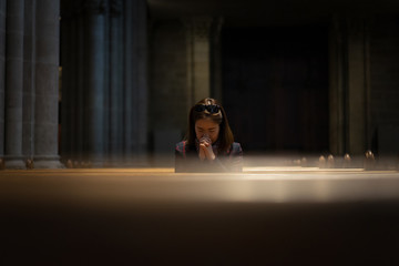 A Christian girl is sitting and praying with broken heart in the church.