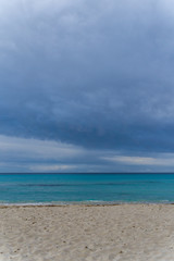 Fototapeta na wymiar Mallorca, Dark cloudy sky over white sand nature beach landscape of Cala Millor