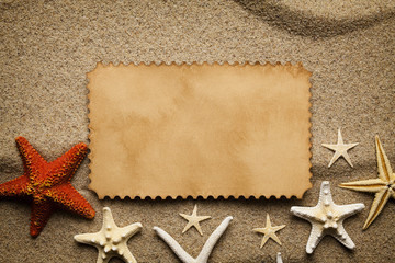 Fototapeta na wymiar Blank paper sheet and starfishes on the beach sand