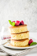 Trendy asian food, Fluffy Japan souffle pancakes, hotcakes with maple syrup and raspberry light concrete background copy space