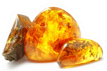 Three bright pieces of amber of different shapes and colors on a white background. Amber texture. A natural mineral for jewelry. Frozen resin with inclusions insects inside. Sun Stone