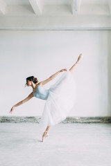 A young ballerina is getting ready, stretched and dancing. Poses in ballet. Photo shoot in the loft Studio. Russian Ballerina at the bench. ballet flats and dance dress © pavelvozmischev