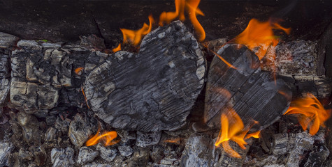 Hot coals and burning woods in the form of human heart. Glowing and flaming charcoal, bright red fire and ash. .Close-up, top view.