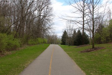 The long straight pathway in the park on a spring day.