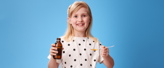 happy child taking spoon of children's suspension on blue © Alliance