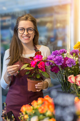 flower seller, young woman standing at shop with  flower in hands happily looks at camera