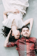 charismatic couple at a photo shoot in European style. Hugging and smiling looking at each other. The casual look and the light airy dress of the girl. the loft Studio, and a beautiful girl