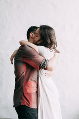 Fototapeta premium charismatic couple at a photo shoot in European style. Hugging and smiling looking at each other. The casual look and the light airy dress of the girl. the loft Studio, and a beautiful girl
