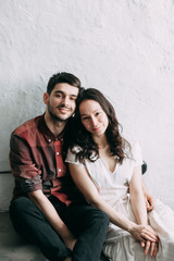 charismatic couple at a photo shoot in European style. Hugging and smiling looking at each other. The casual look and the light airy dress of the girl. the loft Studio, and a beautiful girl