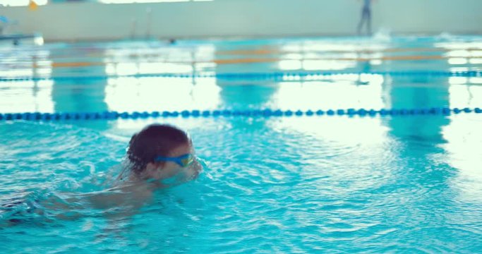 Teen boy professionally swims in the pool