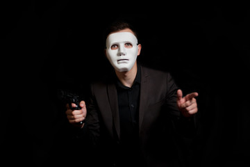 A man in a white mask on a black background, holding a gun. Robber shop, bank