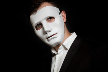 Close-up of a man in a white mask on a black background