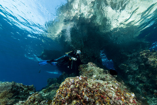 Woman Diver Underwater At The Entrance Of A Cave With Sunrays