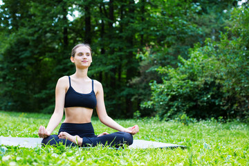Naklejka na ściany i meble Young woman doing yoga in the park.