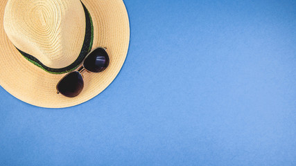 straw hat with sunglasses on a blue background Top view Copyspace Banner concept © Natalya