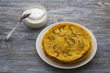 Pancakes with onion, curry and yogurt sauce. on a wooden table. selective focus. delicious homemade food