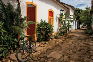 View of cobblestone alley with old house, vegetation and bicycle in Paraty, a historic town totally preserved in the Rio de Janeiro State coast, southwestern Brazil