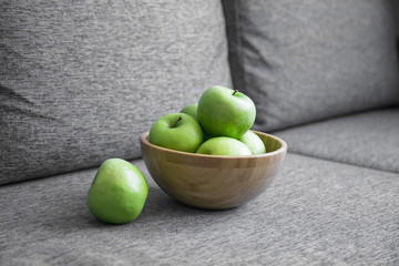 green fresh apples are in a wooden bowl in the kitchen