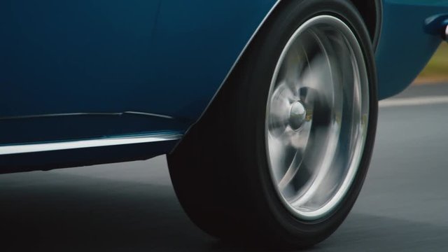 Close up of rear wheel driving down road, blue car