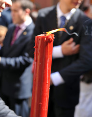 Primer plano de un Cirio encendido rojo. Procesión del Corpus Chistri en el barrio de Triana....