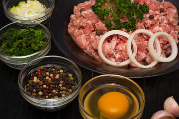 Raw meat beef in a plate with spices on a black cutting board. Fresh stuffing.