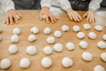 Obraz na płótnie Canvas Forming daugh balls for baking buns on the wooden table at the manufacturing
