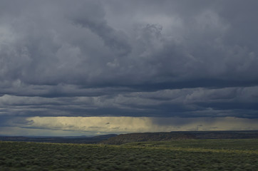 The dark gloomy rain clouds over the desert open range on a spring evening. 