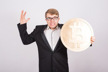 Portrait of a screaming businessman holds big golden bitcoin in his arms. Man in panic of cryptocurrency crash